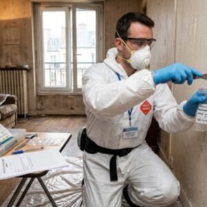 Opérateur en combinaison réalisant un repérage amiante
